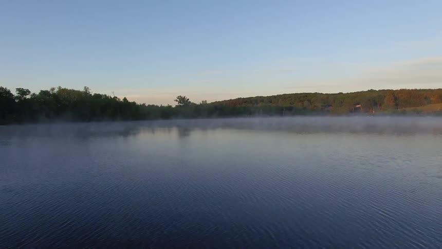 Lake has fog floating on the surface on a sunny day