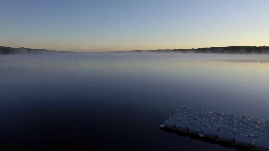 Light fog is on a lake near a pier