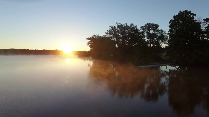 The sun is setting over a fog covered lake