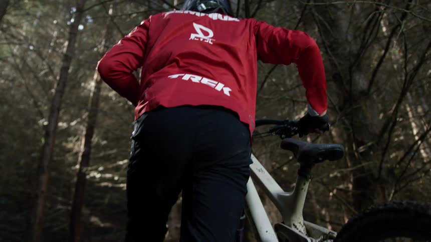 Cyclist pushes bicycle through the trees of a forest