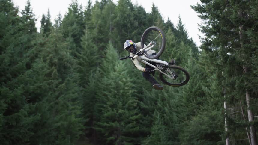 Cyclist rides a bike over a hill and jumps it into the air before landing