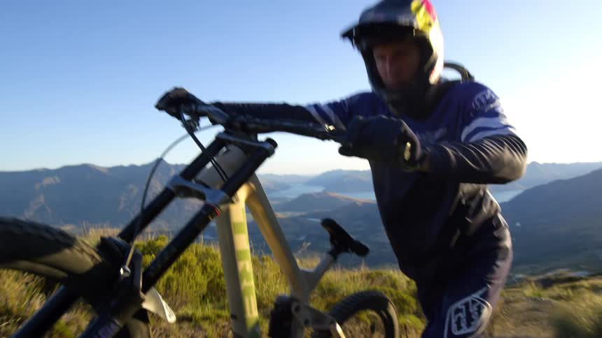 Cyclist pushes off road bicycle up a hill at sunset