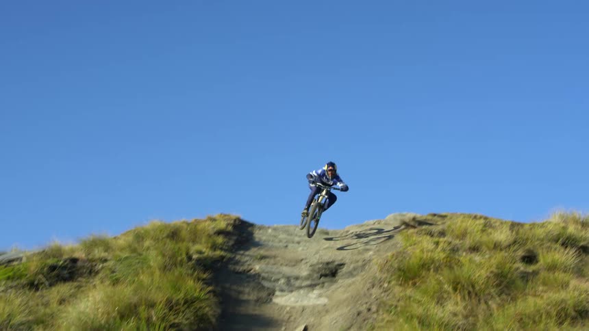A mountain biker jumps over the large hill