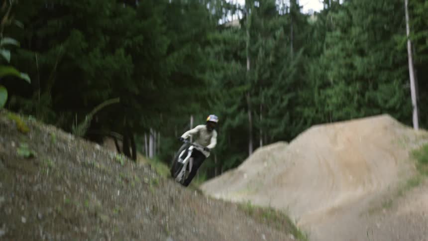 Cyclist jumps over a slope with a mountain bike in the forest