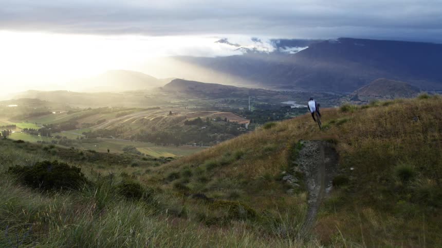 Cyclist ride mountain bike downhill while jumping at sunset