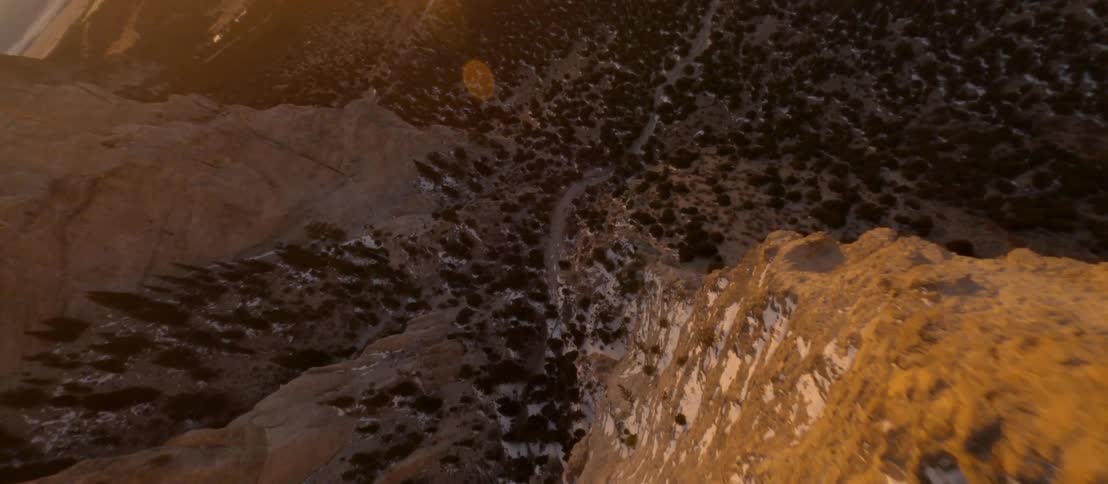 The snowy cliff of a mountain and the patches of vegetation covering the hills below
