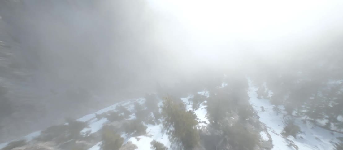 Aerial view of the snow covered slopes of a mountain under the clouds