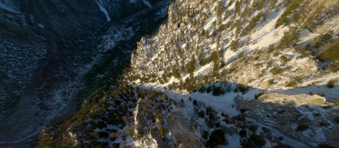 Aerial view of a deep snowy valley and a steep mountain