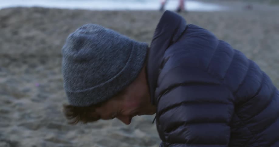 Young man kneeling on the floor cries and punches the sand