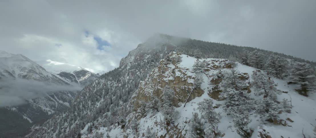Low lying clouds cover valley and peak of snow and forest covered mountain