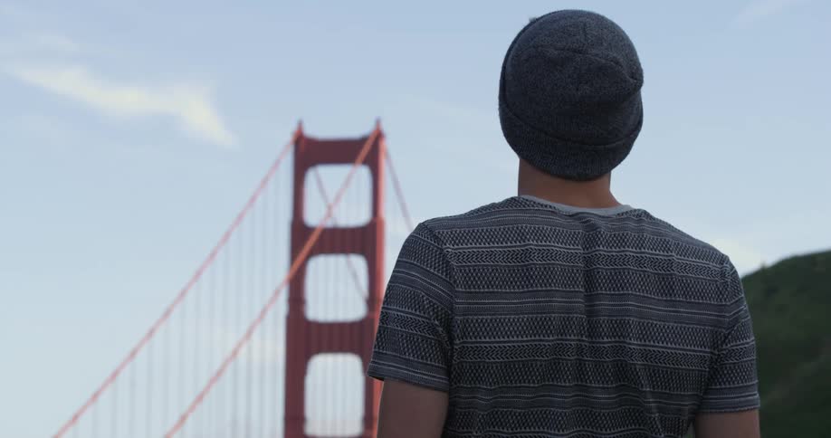 A man stands and looks at a bridge