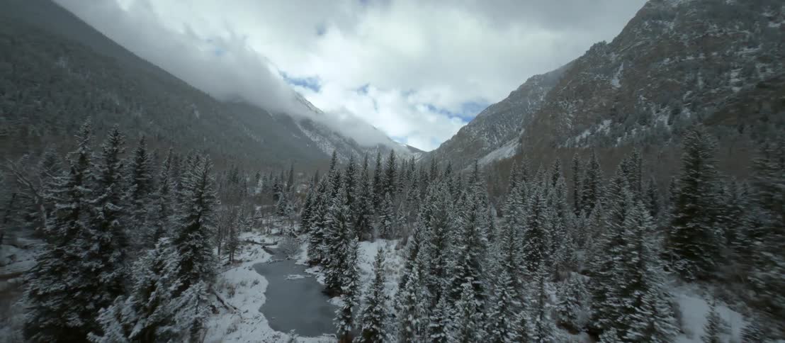 Aerial view of a river flowing through a forest in front of a mountain range