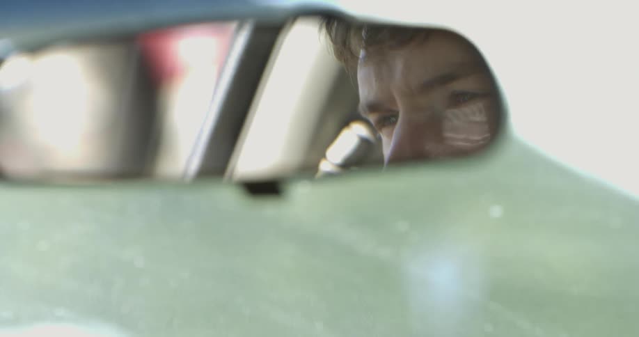 A mans reflection in a rearview mirror as he drives
