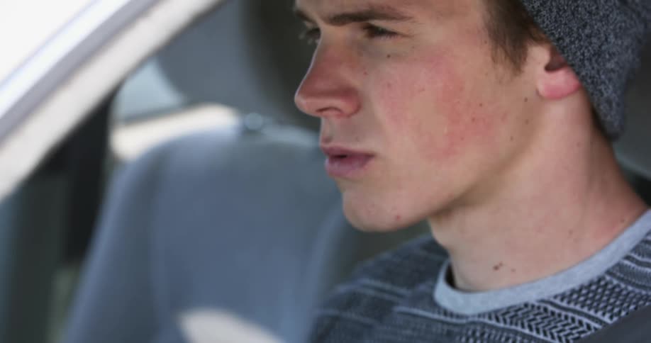 Young man reads a book sitting in a seat inside a car