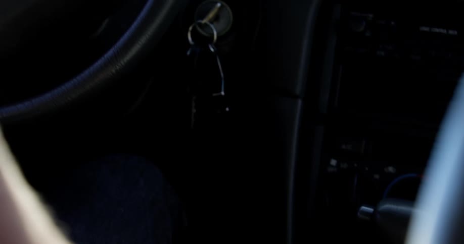A man puts his car in park and removes the keys