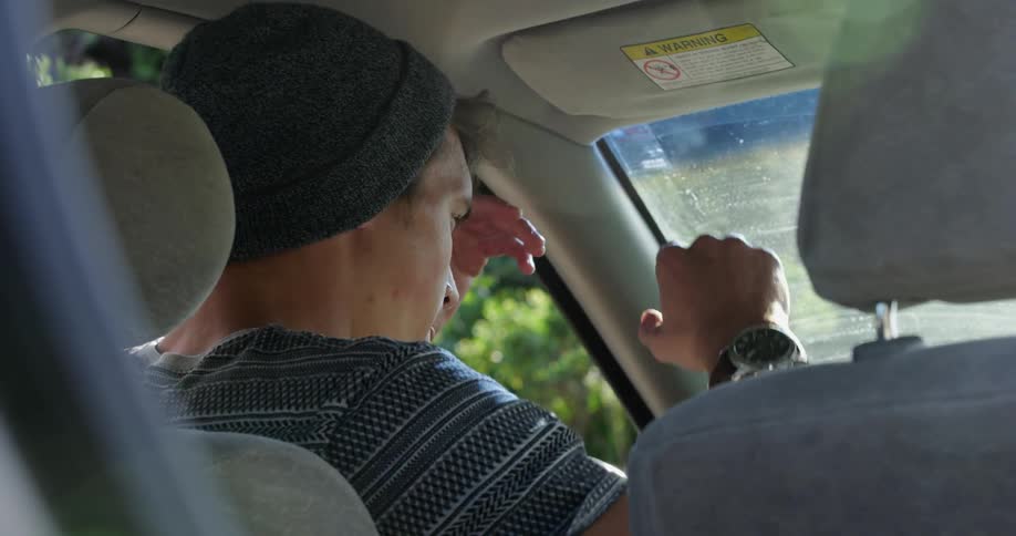 Stressed man with a grey beanie and t shirt sitting in a car breaks down and screams