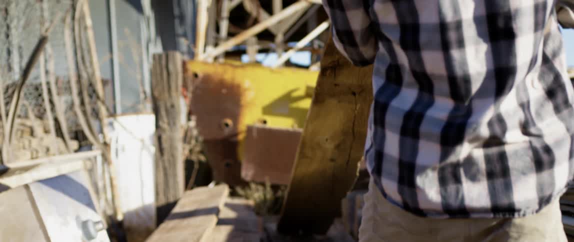 Man lifts abandoned planks of wood on a junk yard