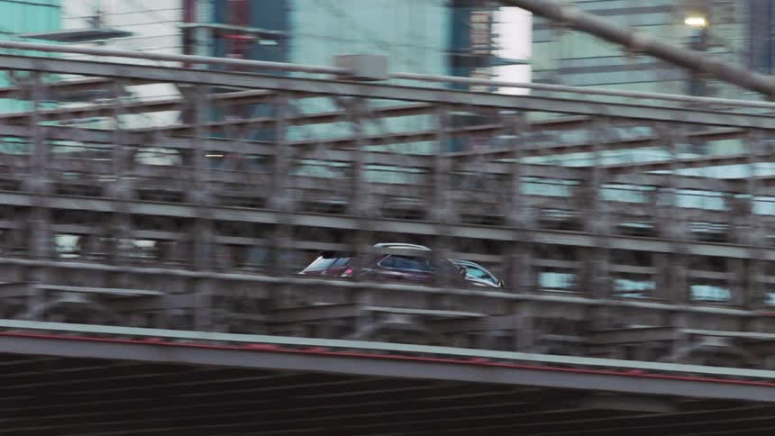 Cars cross a suspension bridge that is supported by strong steel ropes hung from a tower