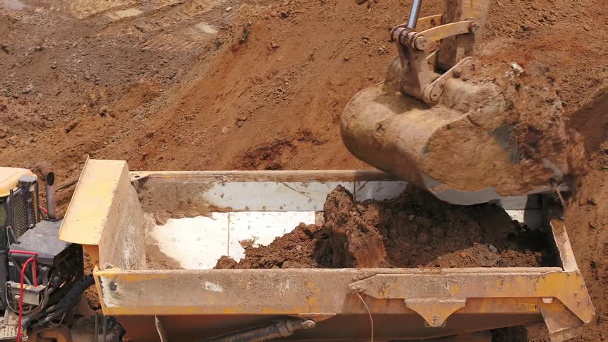 Excavator loading dirt on a dump truck in a construction site