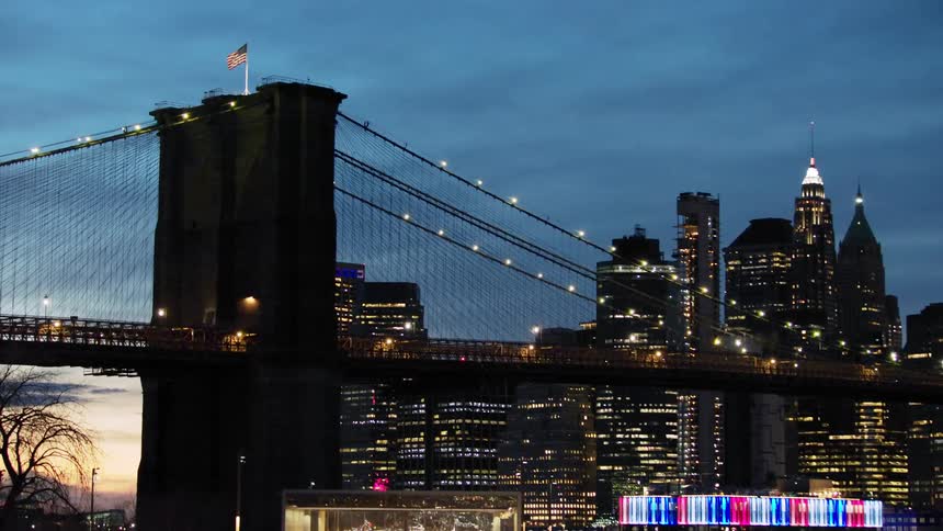 Vehicles travel over the bridge near the city at sunset