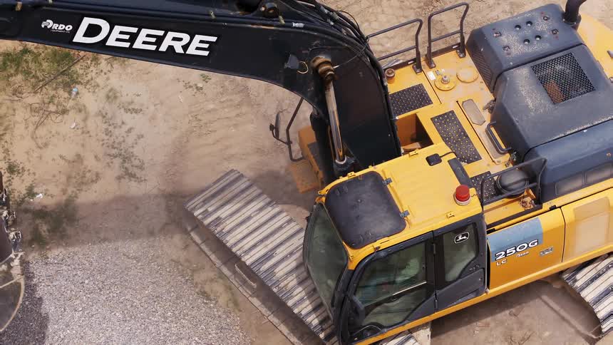 A bulldozer removes dirt from a barren field