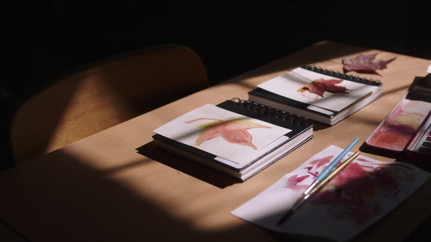 Paints brushes and binders sit on a table