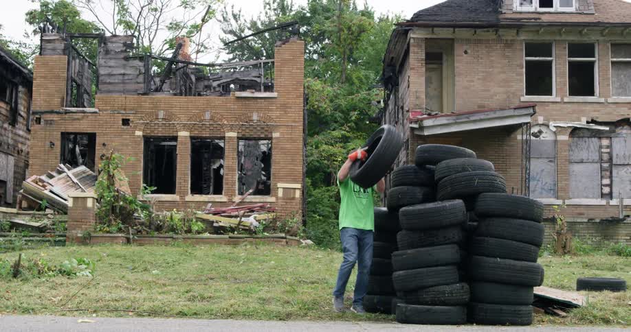 Man carries tires out of abandoned houses and piles them up on the driveway