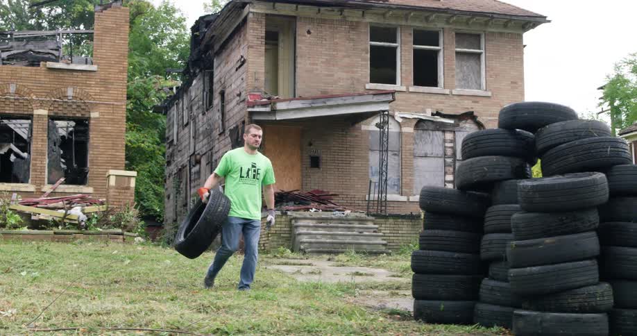 A man cleans up tires in a neighborhood hit be destruction
