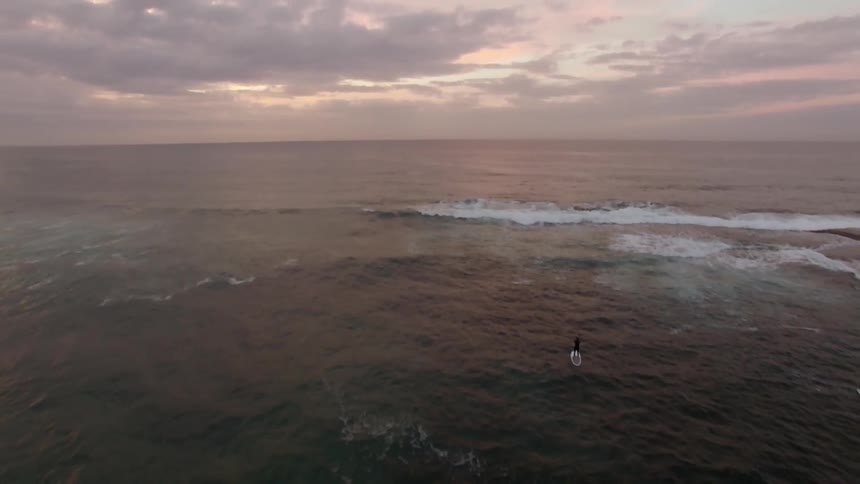 People are surfing in the water at sun set