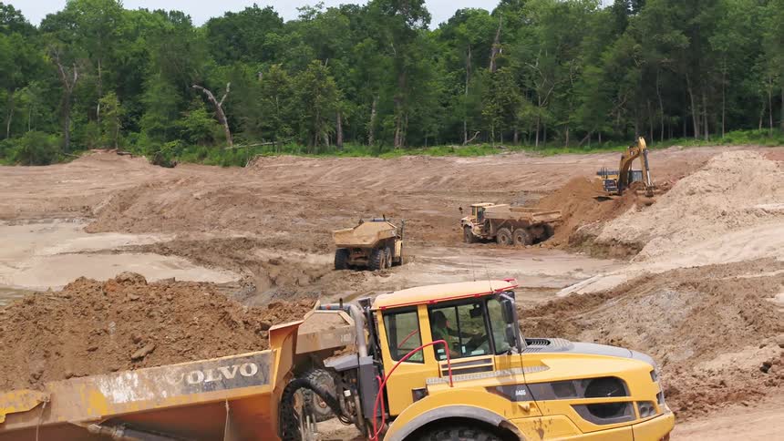 Industrial dump truck filled with dirt drives through construction site