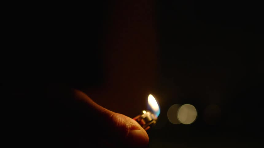 Hand holding a lit lighter at night