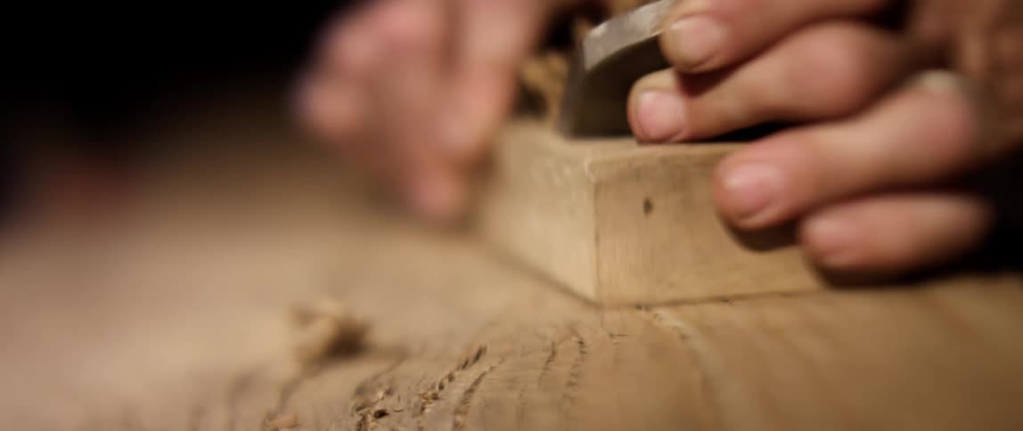 Close up of a wood planer shaving a piece of wood