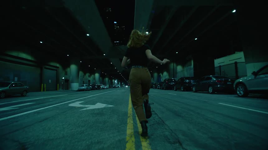 Woman runs along covered street past parked cars
