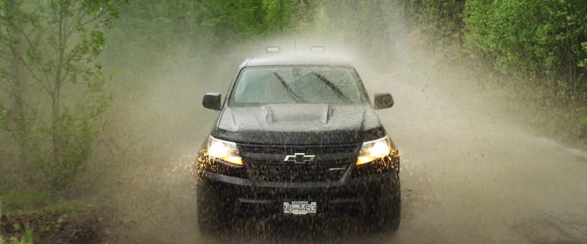 All terrain vehicle drives through water and mud on a rural country road