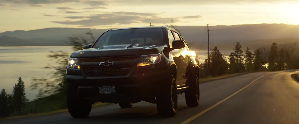 Pickup truck drives uphill at sunset