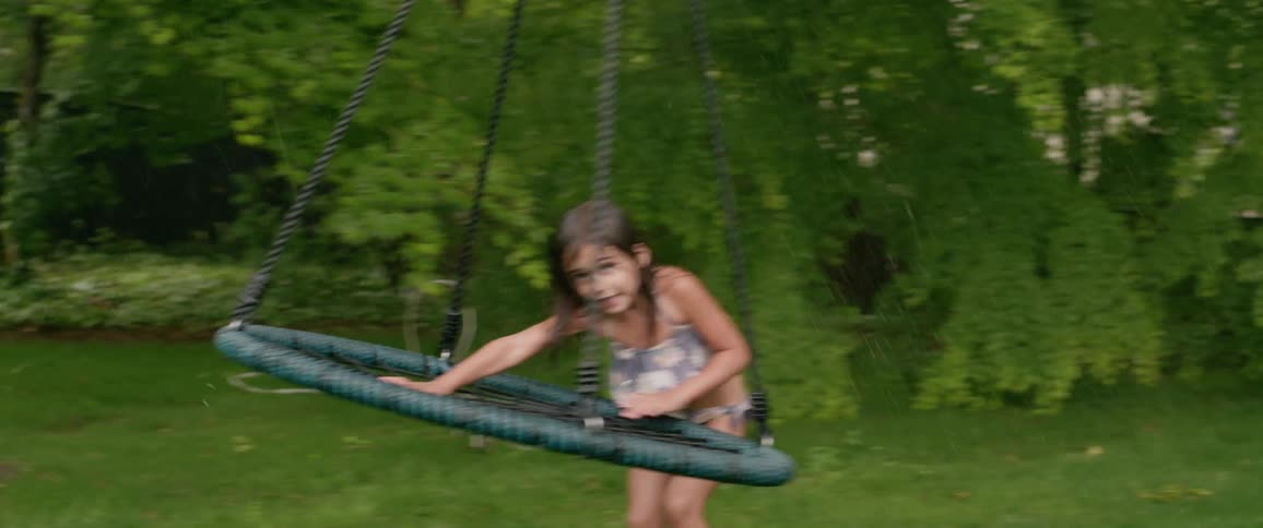 A child swings in the yard as it rains