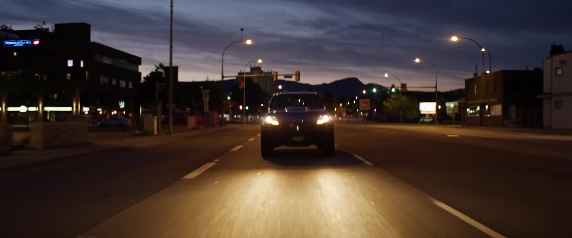 Pickup truck illuminating the road with headlights drives on highway at dawn