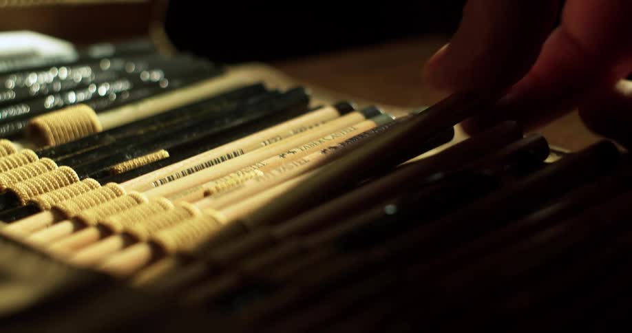 A hand picks a pencil from a drawing kit