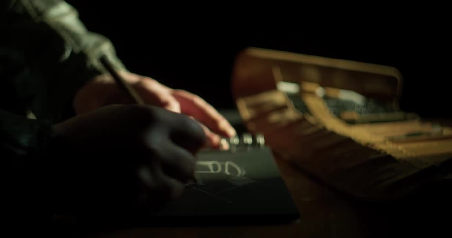 A man uses a silver colored pencil to draw on black paper