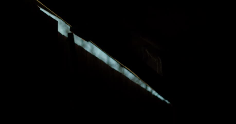 The barn door slowly closes in the dark
