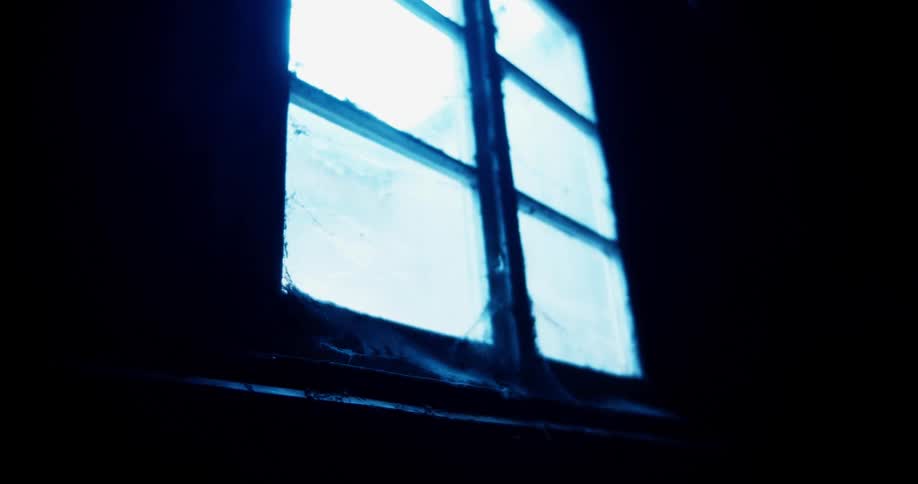 A window with panes and a ripped screen with light glowing through it