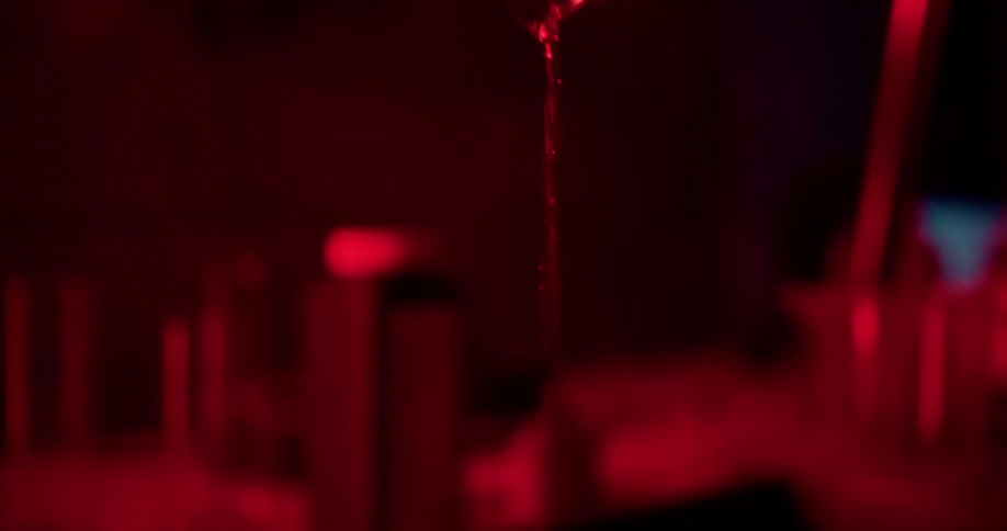 A person pours water into a container in the dark room