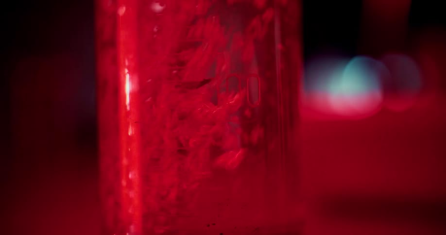 Liquid being poured into a beaker under a red light