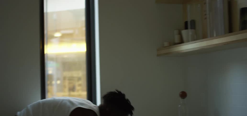 Young man takes dishes out of the dish washer and places them on kitchen shelfs
