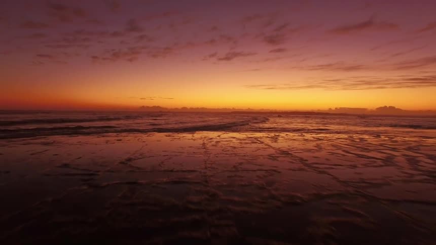 Aerial view of birds flying over water at sunset
