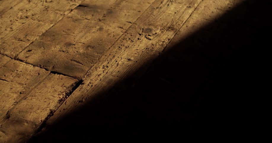 Dark shadow obscures part of weather wood flooring