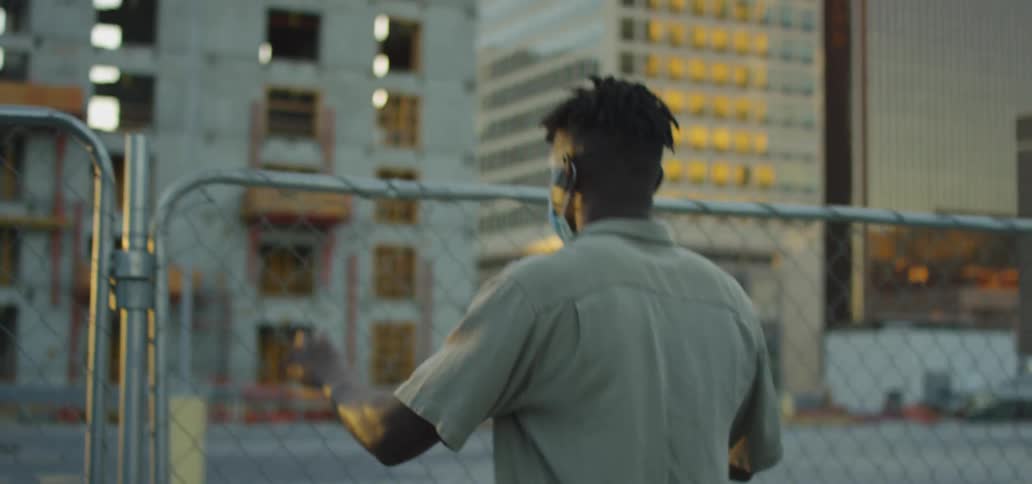 A man in a mask is stuck behind a fence in a downtown city