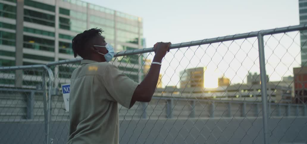 A man jumps to get a better view as he holds onto a chain link fence outside a city building