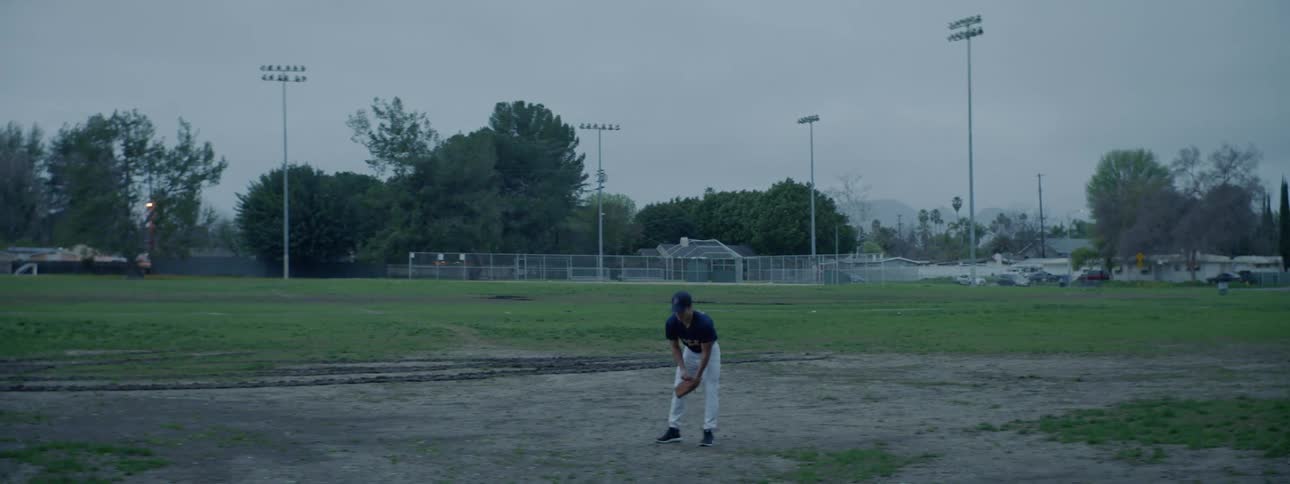 A pitcher bends down in a ball field