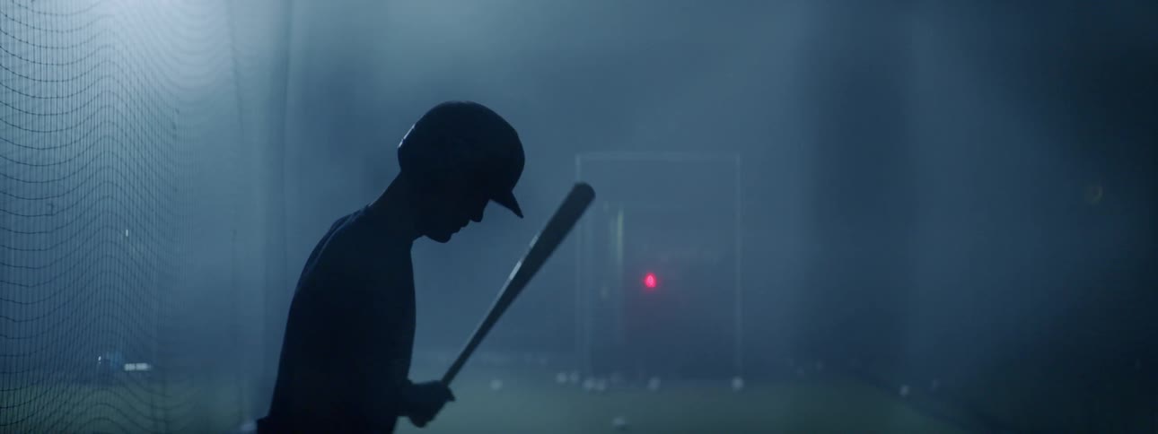 A teenager swings a bat at balls